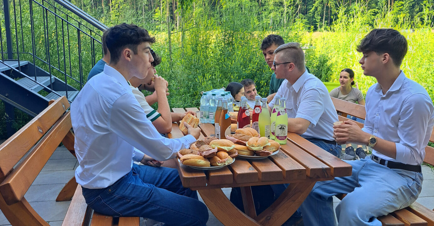 Die Schüler der HTL Pinkafeld auf der Terrasse in der Pause beim Essen von Wurstsemmeln und Getränke